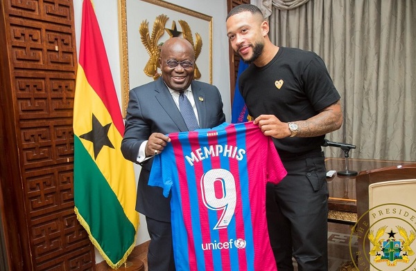 Memphic Depay hands a replica Bercelona jersey to President Nana Addo Dankwa Akufo-Addo